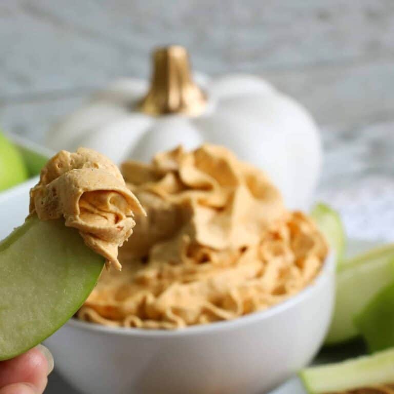 Cool Whip Pumpkin Dip shown in a bowl with apple dipped in whip