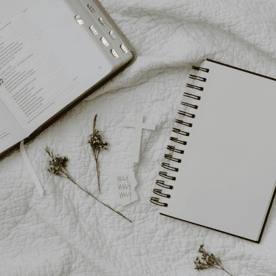 A notebook and a cross on a bed.